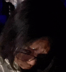 a close up of a woman wearing glasses and a hooded jacket in a dark room .