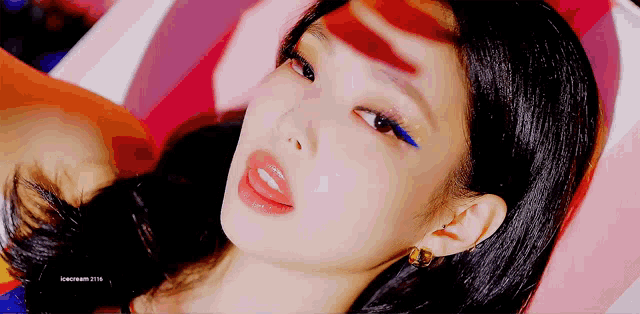 a close up of a woman 's face with a blue eye shadow and red lips .