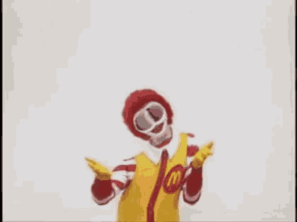 a mcdonald 's clown is dancing with his arms in the air while wearing a red and yellow costume .