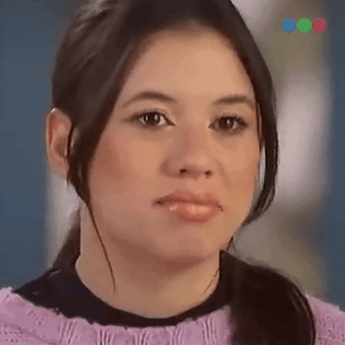 a close up of a woman 's face with a purple sweater and black shirt