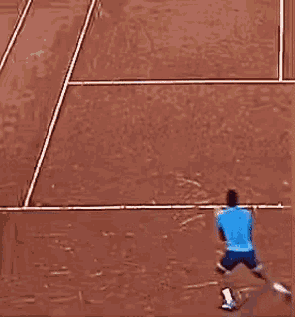 a man in a blue shirt is swinging a tennis racquet