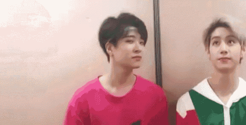 two young men are standing next to each other and looking at each other .