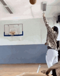 a person is throwing a basketball in the air in a gym