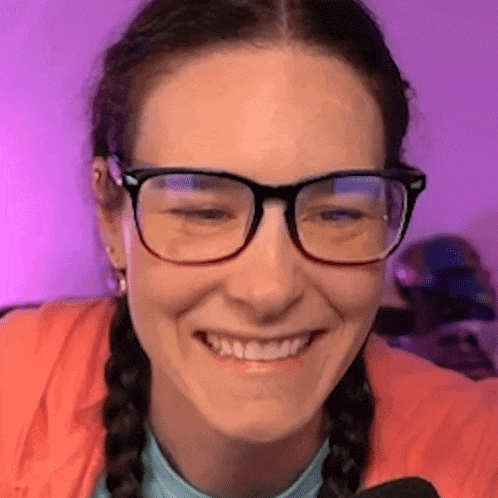 a woman wearing glasses and braids is smiling and looking at the camera