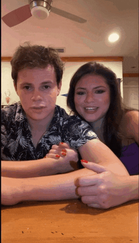 a man and a woman are sitting at a table with their hands on each other