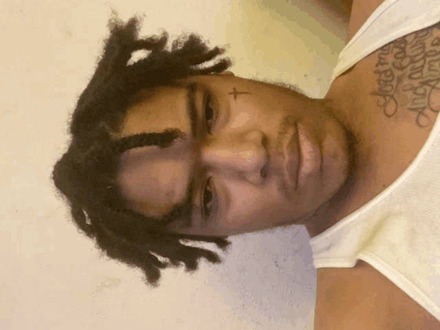 a man with dreadlocks has a tattoo on his face that says " jesus is my angel "