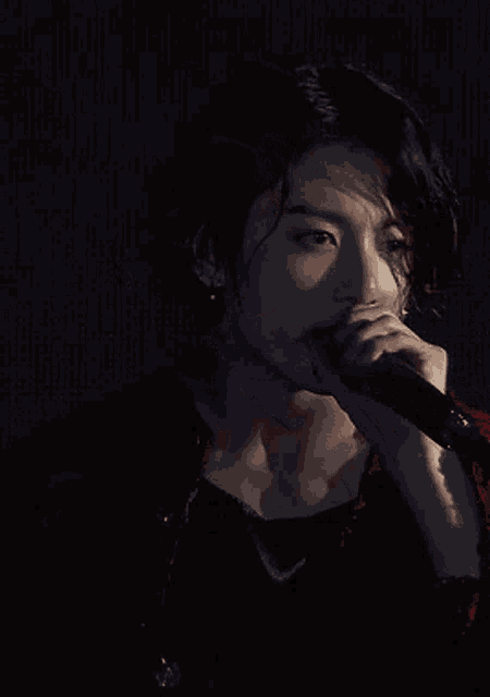 a woman singing into a microphone with a dark background