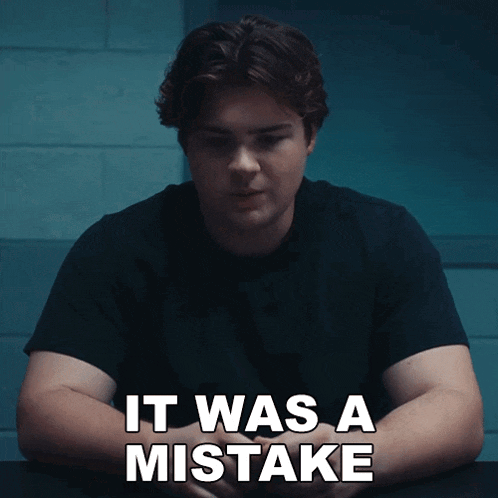 a man sits at a table with the words " it was a mistake " written on the bottom