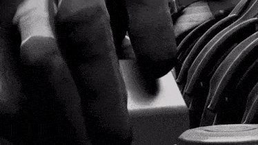 a black and white photo of a person sitting in a row of chairs