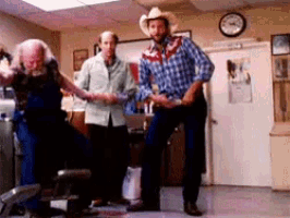 a man in a cowboy hat is dancing in a room with other people