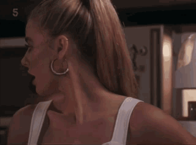 a woman in a white tank top is standing in front of a refrigerator with the number 5 on it