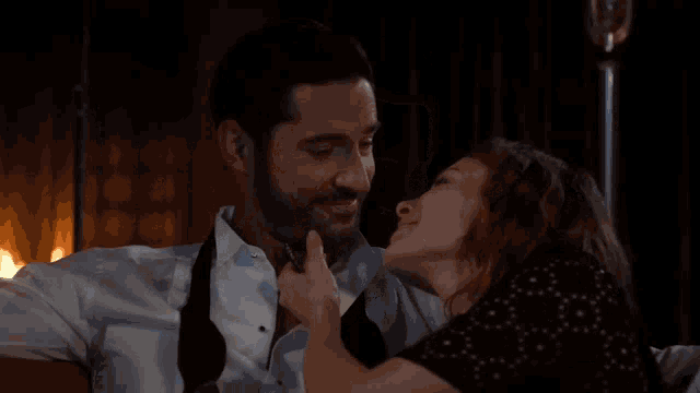 a man and a woman kissing in front of a fireplace