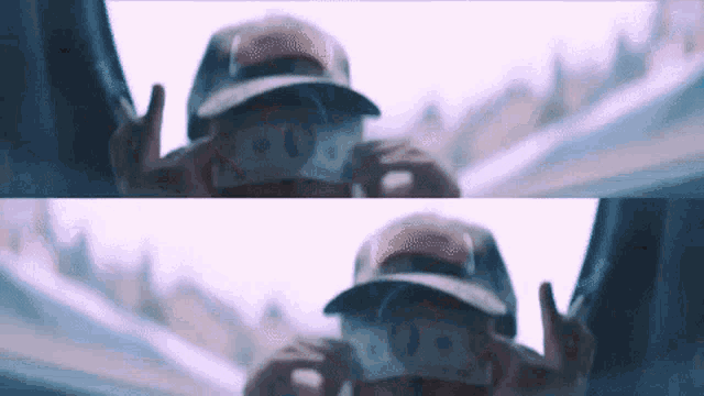 a person wearing a hat is holding a bunch of money in front of their face .