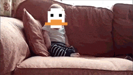a baby is sitting on a couch with a pixelated duck face covering his face