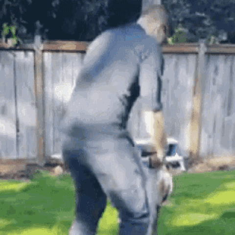 a man is standing on a lawn with a dog .