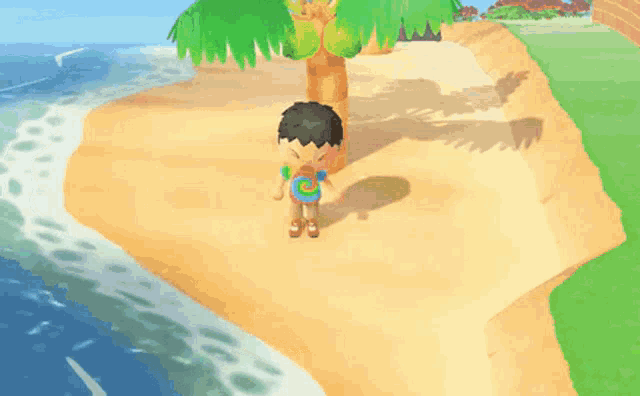 a boy in a tie dye shirt stands on a sandy beach near a palm tree