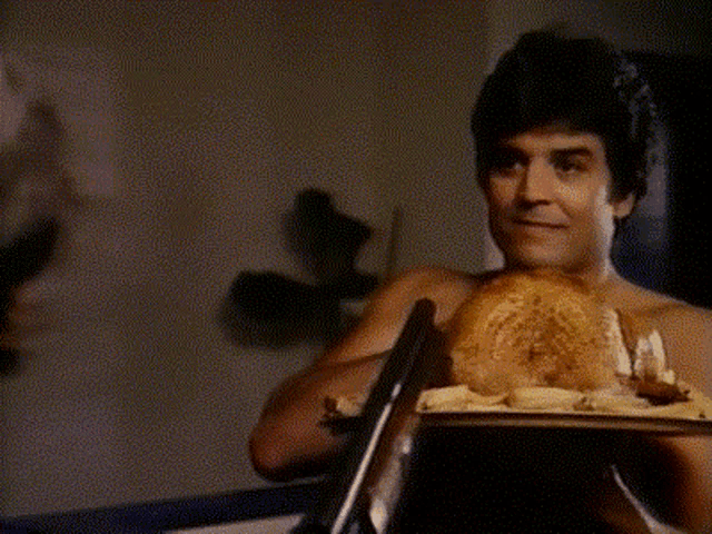 a shirtless man is sitting in a chair holding a tray of food