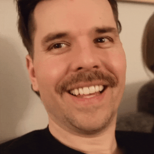 a man with a mustache is smiling with his teeth showing