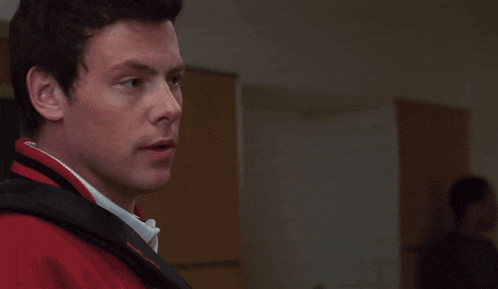 a man wearing a red jacket with a black strap that says columbia on it