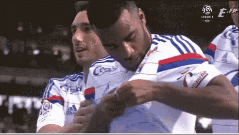 a soccer player is adjusting his shirt while another player watches