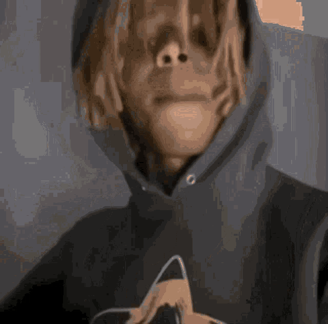 a man with dreadlocks is wearing a hoodie and pointing his finger at the camera .