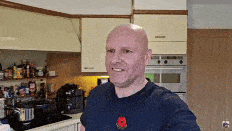 a bald man with a poppy pin on his shirt