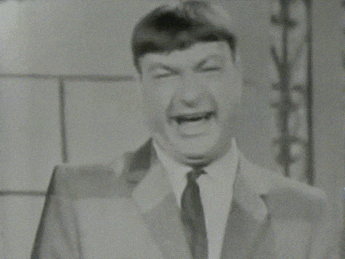 a man in a suit is making a funny face