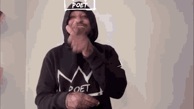 a man wearing a black hoodie with a crown on his head .
