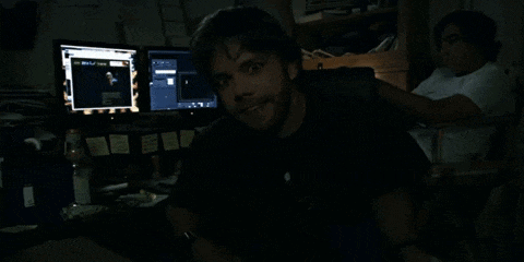 a man in a black shirt is smiling in front of a computer monitor that says ' microsoft ' on it