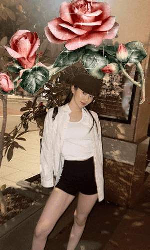 a woman in a white shirt and black shorts stands in front of a painting of roses