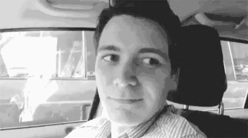 a man is sitting in the driver 's seat of a car .