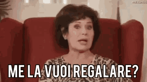 a woman is sitting in a red chair with the words me la vuoi regalare written on her face .