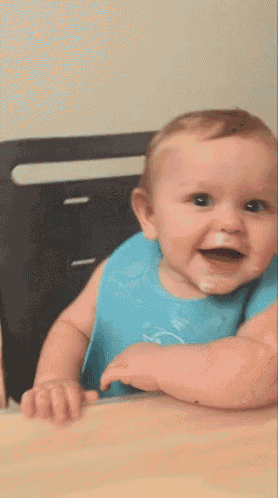 a baby is wearing a blue bib and smiling