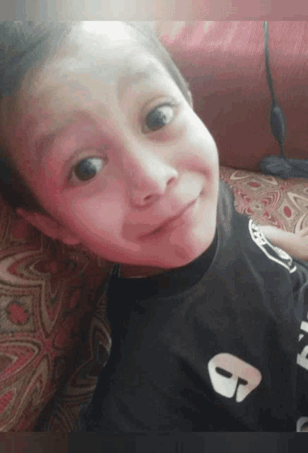 a young boy wearing a black shirt with a white letter b on it