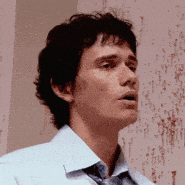 a man in a blue shirt and tie is looking up at something