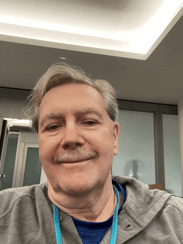 a man with a blue lanyard around his neck smiles