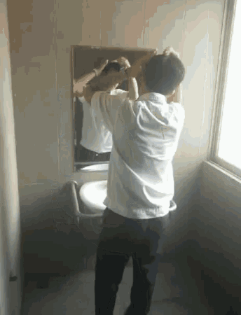 a man in a white shirt is standing in front of a mirror