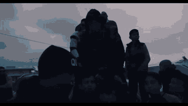 a man wearing a black hat with the letter q on it is carrying a group of children
