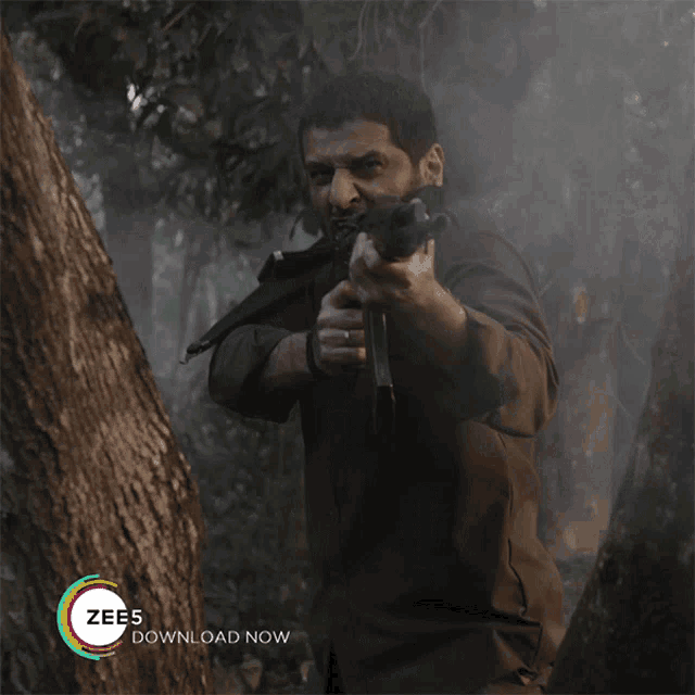 a man holding a gun in the woods with a zees download now advertisement