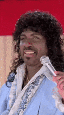 a man with curly hair and a beard is smiling while holding a microphone