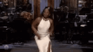 a woman in a white dress is dancing on a stage in front of a band .