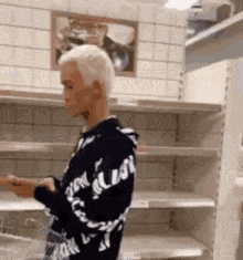 a man is standing in front of empty shelves in a store holding a shopping cart .
