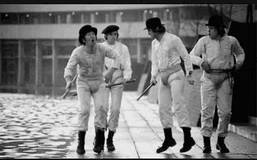 a black and white photo of four men walking down a sidewalk .