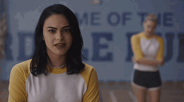 a girl stands in front of a blue wall that says home of the devil