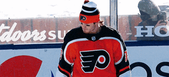 a hockey player wearing a flyers jersey stands in front of a honda sign