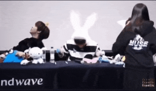a group of people sitting at a table with muse written on their back
