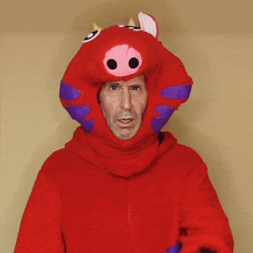 a man wearing a red pig costume with purple ears and horns