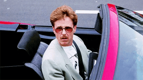 a man wearing sunglasses is sitting in a convertible car