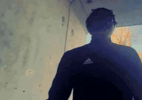 a man in a black adidas jacket is walking