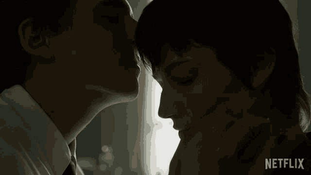 a man kissing a woman on the forehead with a netflix logo in the background